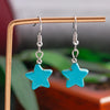 Turquoise star-shaped earrings on a stand with a blurred background