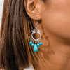 Close-up of an earring with turquoise beads worn by a person.