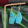 Blue cat-shaped earrings on a stand with a green leafy background