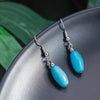 Turquoise earrings with silver hooks on a dark surface