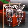 Butterfly earrings with black beads on a wooden stand