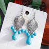 Silver earrings with turquoise beads on a white card
