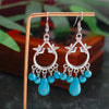 Silver earrings with blue beads on a wooden stand with a blurred natural background