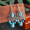Turquoise earrings with silver accents on a wooden surface