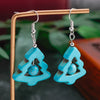 Turquoise earrings on a stand with a blurred natural background