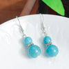 Turquoise beaded earrings on a white plate with a blurred background