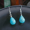 Turquoise teardrop earrings on a dark surface