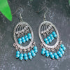 Pair of silver earrings with turquoise beads on a dark background