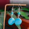 Turquoise earrings on a stand with a blurred natural background