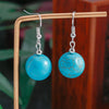 Turquoise earrings on a wooden stand with a blurred background
