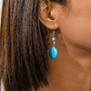 Close-up of a turquoise earring worn by a person with dark hair.