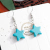 Star-shaped earrings with turquoise stones on a white card.