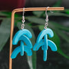 Turquoise earrings on a stand with a blurred green leafy background