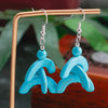Turquoise earrings with a silver hook on a stand against a blurred natural background