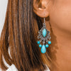 Turquoise earrings with silver details worn by a person with brown hair.