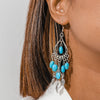 Turquoise beaded earrings with silver hooks worn by a person with brown hair.