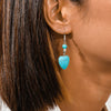 Turquoise heart-shaped earring worn by a person with dark hair.