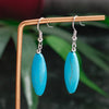 Turquoise earrings on a stand with a blurred green background