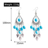 Pair of blue beaded earrings with feather charms, shown with measurements on a white background.