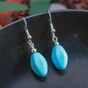 Turquoise earrings with silver hooks on a dark surface