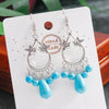 Pair of silver earrings with turquoise beads on a 'Handmade' card.