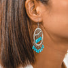 Close-up of a woman wearing a silver earring with turquoise beads.